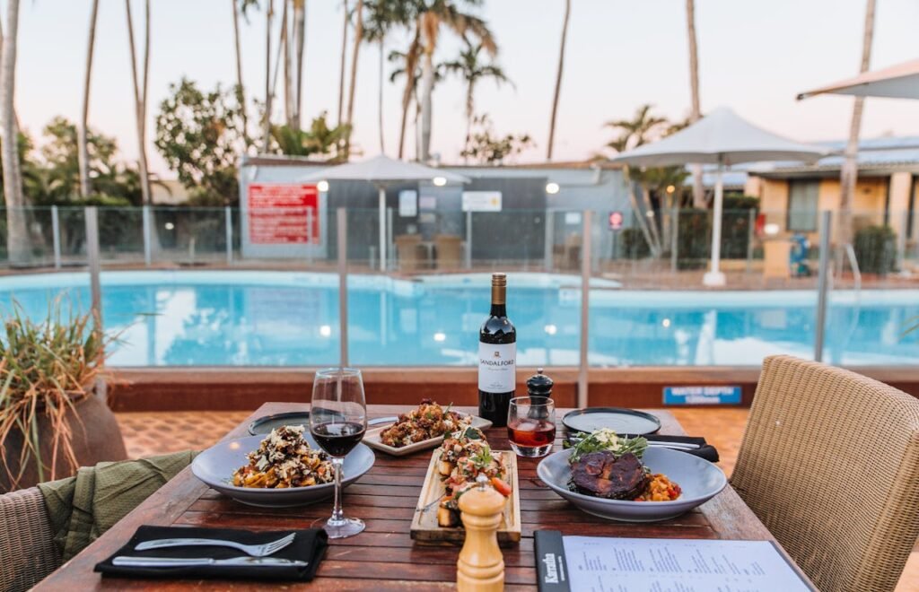 A delicious Italian meal served poolside, featuring assorted dishes and red wine.