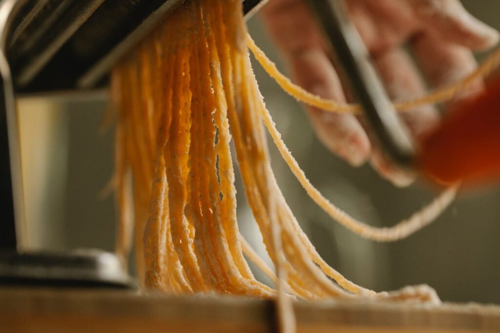 Fresh pasta being cut with a pasta machine, highlighting the art of Italian cooking.